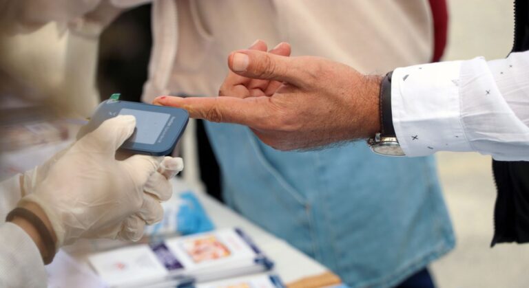 Un profesional de la salud mide la glucosa en el dedo de un paciente con un glucómetro